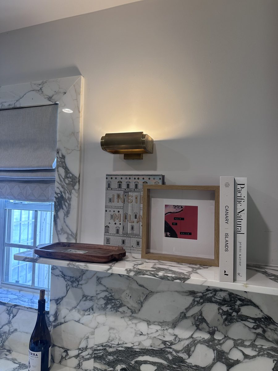 Kitchen marble shelf with art, books and brass sconce